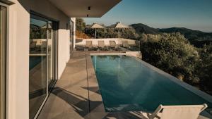 a swimming pool on a patio with chairs and a house at The View Premium Villas in Perdika