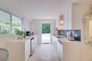 a kitchen with white cabinets and a large window at Walk to Beach Tavernier Apartment with Patio! in Tavernier