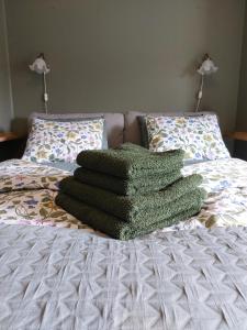 a pile of green blankets on a bed at Woxy Lilaloppan - privacy, space and nature in Voxnabruk