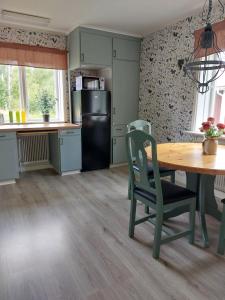 a kitchen with a table and a black refrigerator at Woxy Lilaloppan - privacy, space and nature in Voxnabruk +16 photos