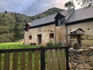 an old stone building with a wooden fence at Superbe grange sur une colline in Asté