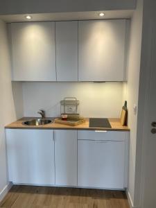 eine Küche mit weißen Schränken und einer Spüle in der Unterkunft Farmhouse in Montaigu-Vendée