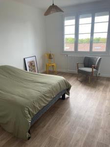 ein Schlafzimmer mit einem Bett und einem Stuhl und Fenstern in der Unterkunft Farmhouse in Montaigu-Vendée