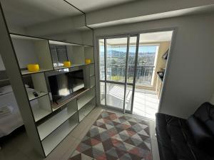 a room with a television and a balcony with a view at Studio Cidade Maia Guarulhos 17! in Água Boa