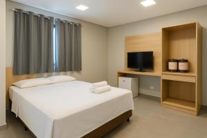 a bedroom with a white bed and a television at Hs Hotel Morumbi in São Paulo
