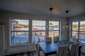 a dining room with a blue table and views of the water at Exclusive fjordside villa with swimming pool, sauna, jacuzzi and boat hire in Sveio