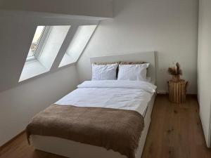 a bedroom with a large white bed with two windows at A&A Apartment in Oftringen +8 photos