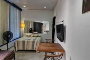 Habitación con cama, TV y mesa. en Apto203 a 100 mts do Shopping Carioca, Brt e Metrô, en Río de Janeiro
