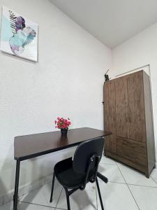 a desk with a chair and a vase of flowers at Estúdio Ventos e flores ate 07 pessoas no Centro in Rio Branco