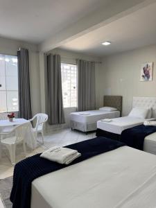 a hotel room with three beds and a table at Estúdio Ventos e flores ate 07 pessoas no Centro in Rio Branco