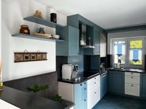 a kitchen with blue cabinets and black counter tops at Ferienhaus Rennsteiggruss in Lauscha