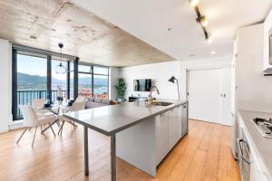 a kitchen and living room with a table and chairs at Stylish 2BR Loft in Historic Gastown with Mountain Views in Vancouver