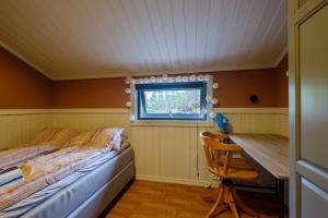 a bedroom with a bed and a desk and a window at Exclusive fjordside villa with swimming pool, sauna, jacuzzi and boat hire in Sveio +44 photos