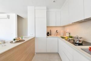 a white kitchen with white cabinets and a counter at Kaiman 41 by VillaGranCanaria in Salobre +72 photos