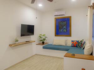 a living room with a blue couch and a tv at Aldea San Lam - Oasis Of Tulum in Tulum