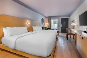a large white bed in a hotel room at voco Kissimmee Orlando by IHG in Orlando