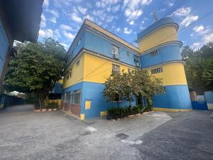 a blue and yellow building with a tree in front of it at Hotel Arsenal in São Gonçalo