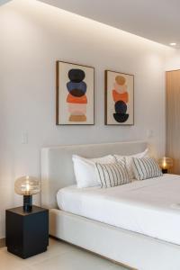 a white bedroom with a bed with three pictures on the wall at Costa Elena at Naumi, Ocean Views & Beach Club in Sardinal