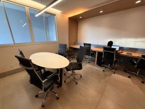 a person sitting at a desk in a room with tables and chairs at City House Exclusive - By Caracol Urbano in Barreiras +222 photos