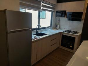 a small kitchen with a refrigerator and a sink at Prados del Oeste in Cochabamba