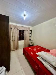 a bedroom with a red bed and a window at Caiçara's house in Praia de Araçatiba +32 photos