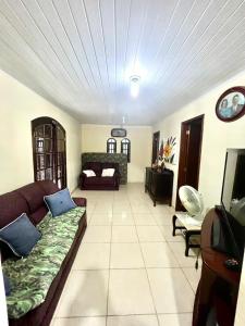 a living room with a couch and a television at Caiçara's house in Praia de Araçatiba