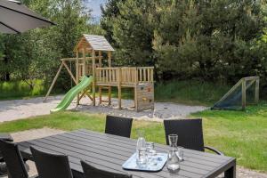 un tavolo con sedie e un parco giochi con un tavolo di legno di BV259-Blavand-Almosetoften-17 a Blåvand