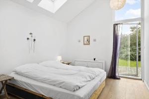 a white bedroom with a bed and a large window at 873-Melby-Bygtoften-3 in Melby