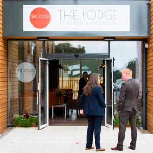 un hombre y una mujer parados fuera de la cabaña en ocho rockhouse en The Lodge At Perth Racecourse en Perth