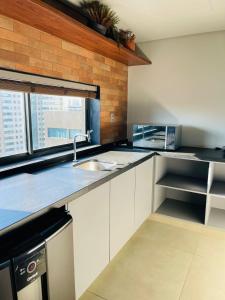 a kitchen with white cabinets and a sink and a window at Art Studio Carimbamba, Jóia Rara! in Salvador