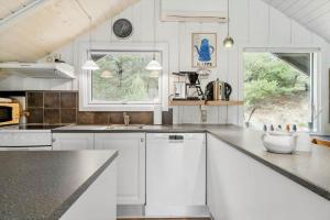 una cucina con mobili bianchi e un piano di lavoro nero di BV150-Blavand-Hedevej-14 a Blåvand Altre 15 foto