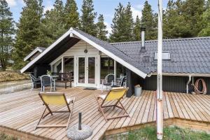 una casa con una terrazza in legno con sedie sopra di BV150-Blavand-Hedevej-14 a Blåvand