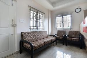 une salle d'attente avec deux chaises et une horloge au mur dans l'établissement Super Hotel O Indra Comforts, à Belagula