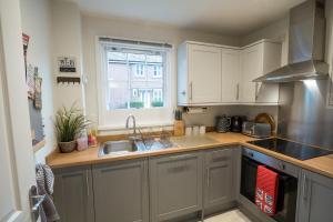 a kitchen with white cabinets and a sink and a window at Relaxing Town Centre House - Perfect for Exploring in Shrewsbury