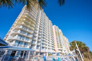 a tall building with a palm tree in front of it at Condo near Barefoot Landing w beach access in Myrtle Beach