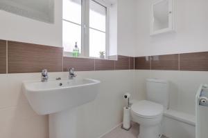 un bagno bianco con lavandino e WC di Spacious 3-Bed House with Parking and Garden ad Aylesbury Altre 22 foto