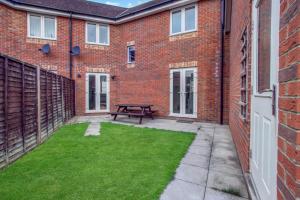 un patio con tavolo da picnic di fronte a un edificio in mattoni di Spacious 3-Bed House with Parking and Garden ad Aylesbury