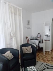 a living room with two chairs and a table at villa arc en ciel in Contrexéville