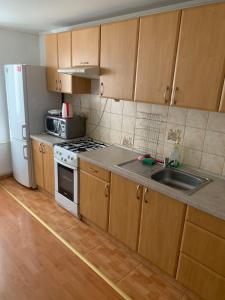 Una cocina con gabinetes de madera, un fregadero y un refrigerador. en Your home 22, en Košice