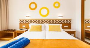 a bedroom with a large white bed with yellow pillows at Globales Santa Ponsa Park in Santa Ponsa +29 photos