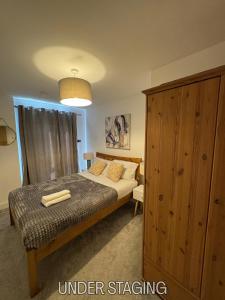 a bedroom with a bed and a wooden cabinet at Grover Court - Modern Stay with Free Gated Parking & WiFi in Kings Langley
