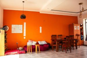 a dining room with an orange wall and a table and chairs at Xenia house in Kigali