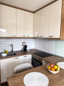 a kitchen with white cabinets and a bowl of fruit on a table at Limpio Apartman 2 in Belgrade +43 photos