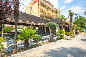 a restaurant with chairs and trees in front of it at Grand Hotel in Elbasan