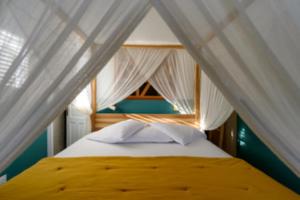 a bedroom with a bed with white curtains at Chez Marie & Philippe - La Villa By Ferdi'Nan in Grand-Bourg