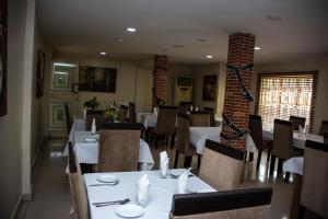 een restaurant met witte tafels en stoelen en een bakstenen muur bij Noah's Ark Hotel & Suites in Maroko