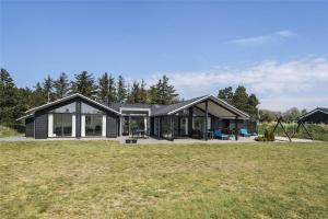 a house with a black roof on a grass field at BV155-Blavand-Gronnevaenget-1-D in Blåvand