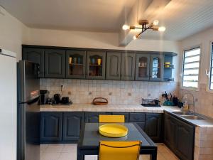 a kitchen with blue cabinets and a table with yellow chairs at TI-KAZ fleurie, l'escapade bouillonaise in LʼAjoupa-Bouillon