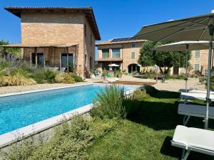 a swimming pool in front of a house with an umbrella at Bricco Aivè in Costigliole dʼAsti
