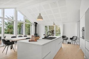 a kitchen with white cabinets and a table with chairs at BV208-Blavand-Strandparken-16 in Blåvand